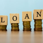 Loan text written on wooden block with stacked coins