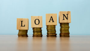 Loan text written on wooden block with stacked coins