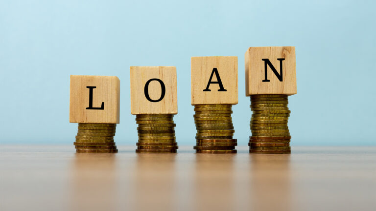 Loan text written on wooden block with stacked coins